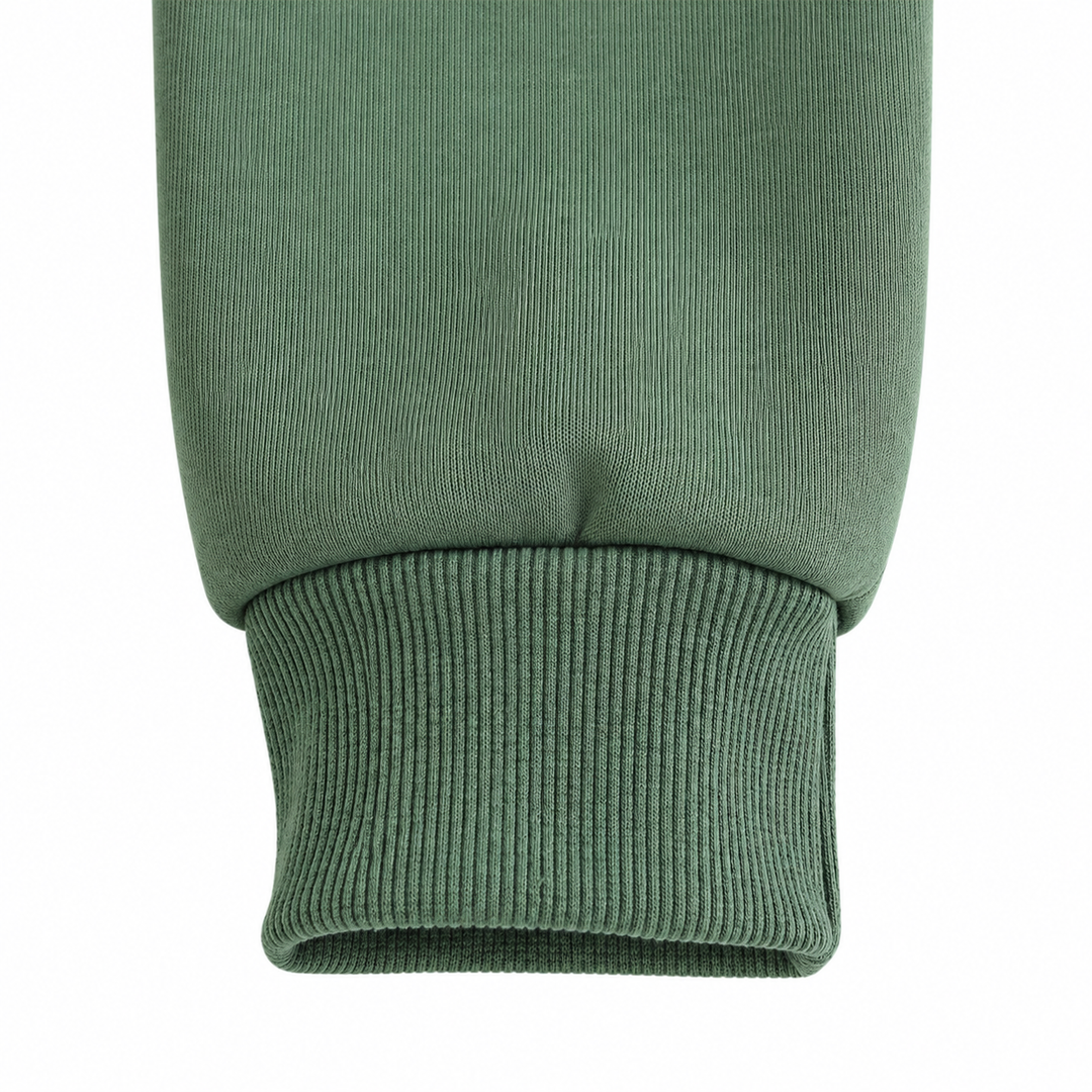 Close-up of the olive green sweatshirt sleeve cuff, showing ribbing, stitching and fabric folds against clean white backdrop.