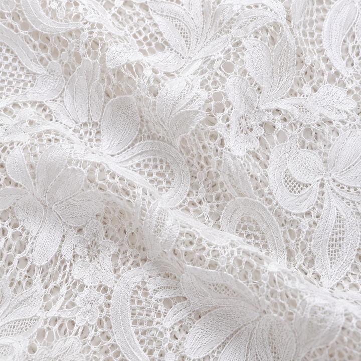 Close view of the white floral lace fabric and its openwork pattern. The floral lace can be seen across the pictured garment.