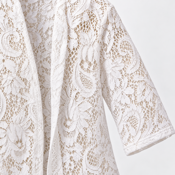 Close view of the white cardigan front edge and three-quarter sleeve. The floral lace is visible across the pictured garment.