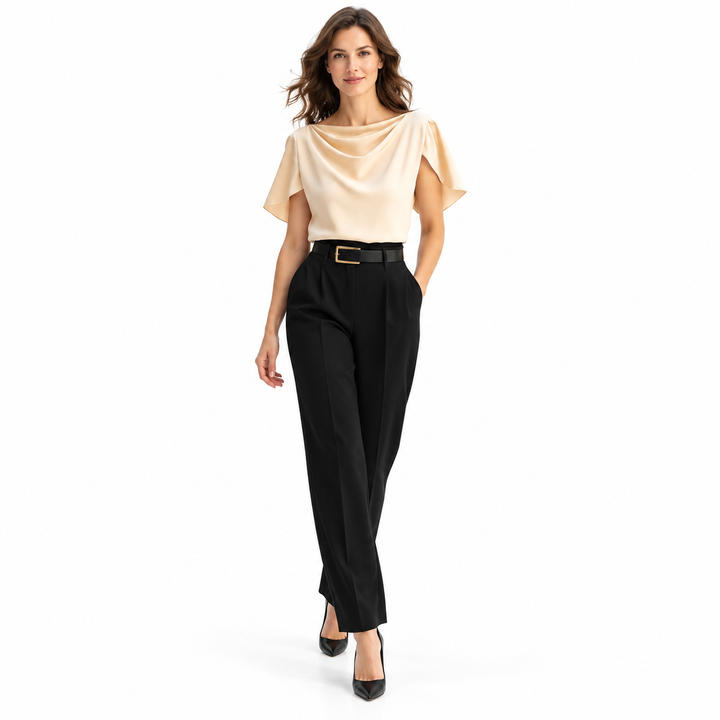 Apricot blouse styled with black trousers and heels on the model in a walking stance, photographed against a white background