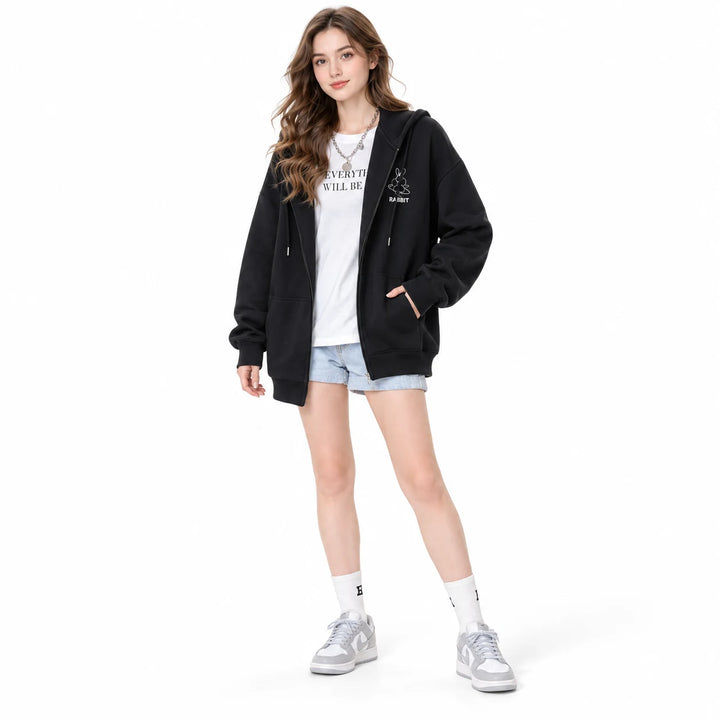 Embroidered zip up hoodie in Black worn by an adult woman, showing rabbit embroidery and pockets, against a white background.