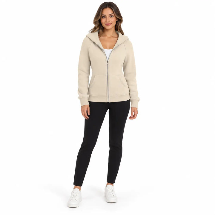 Studio model wearing the Cream Beige zip hoodie, showing a front zipper, hood and ribbed cuffs, on white with black trousers.