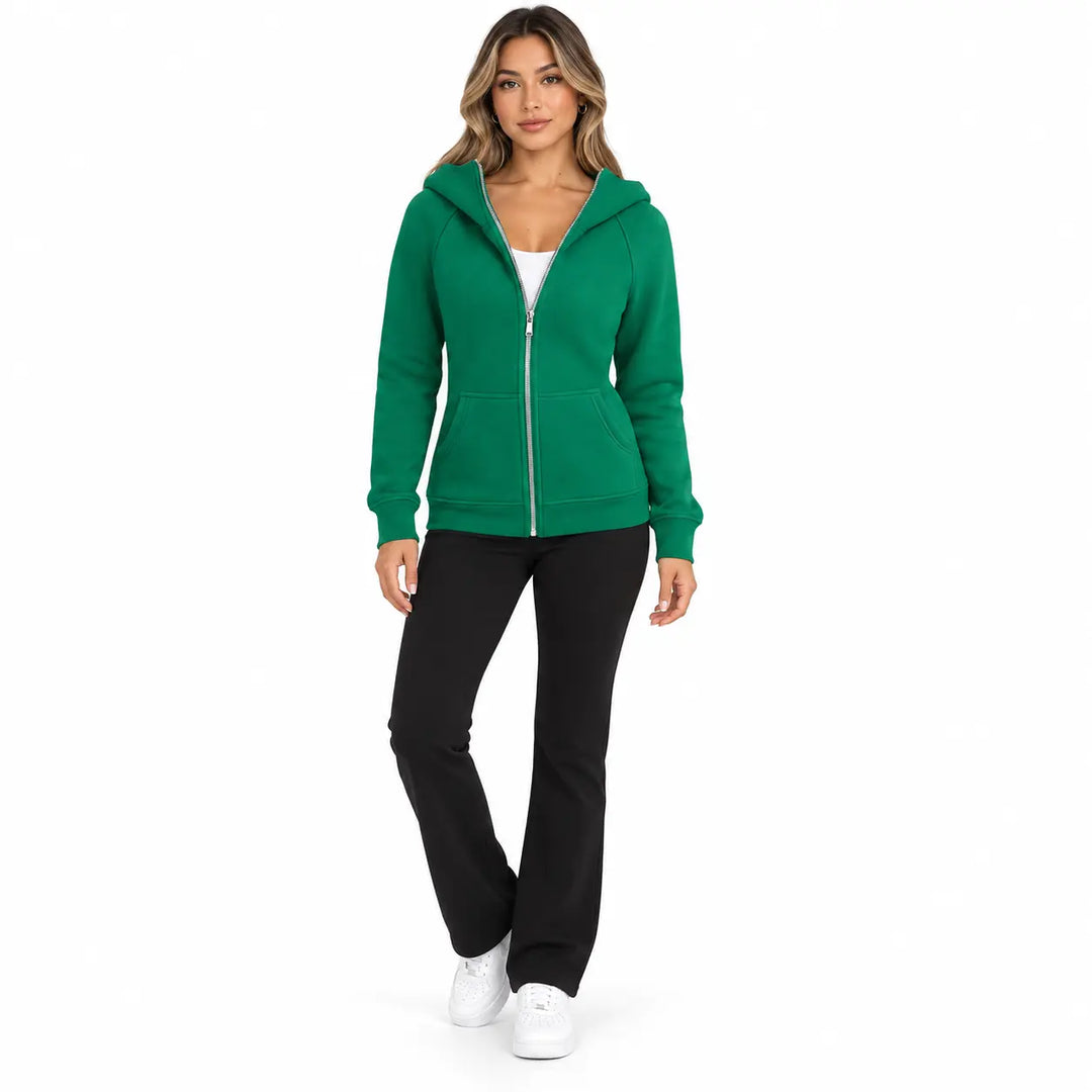 Studio model wearing the Emerald Green zip hoodie, showing front pockets, ribbed cuffs and hem, on white with black trousers.