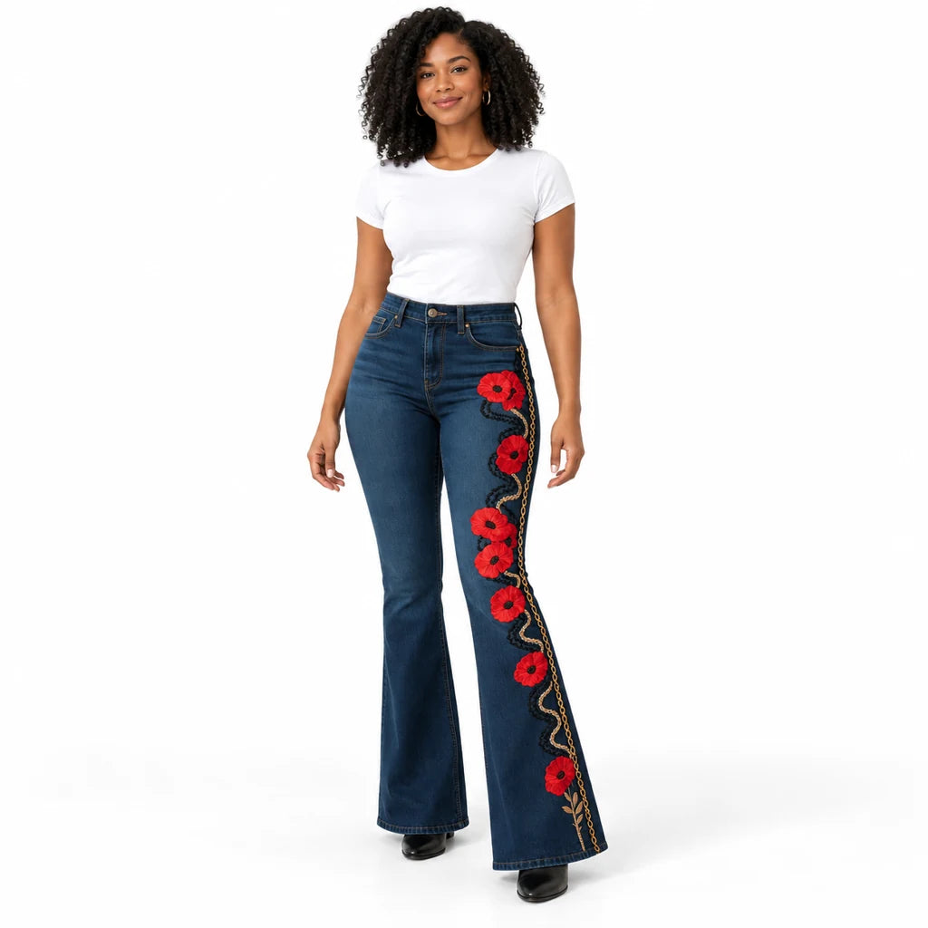 Model wearing dark blue flared jeans with red poppies and a black and gold-tone vine print down one leg shown from the front.