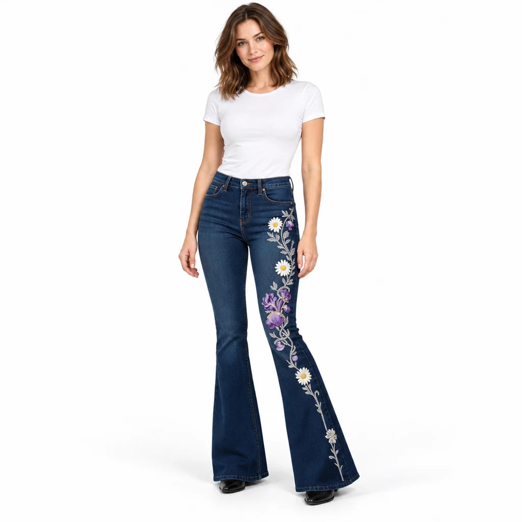 Front view of a model in dark blue flared jeans with purple irises and white daisies printed down one leg.