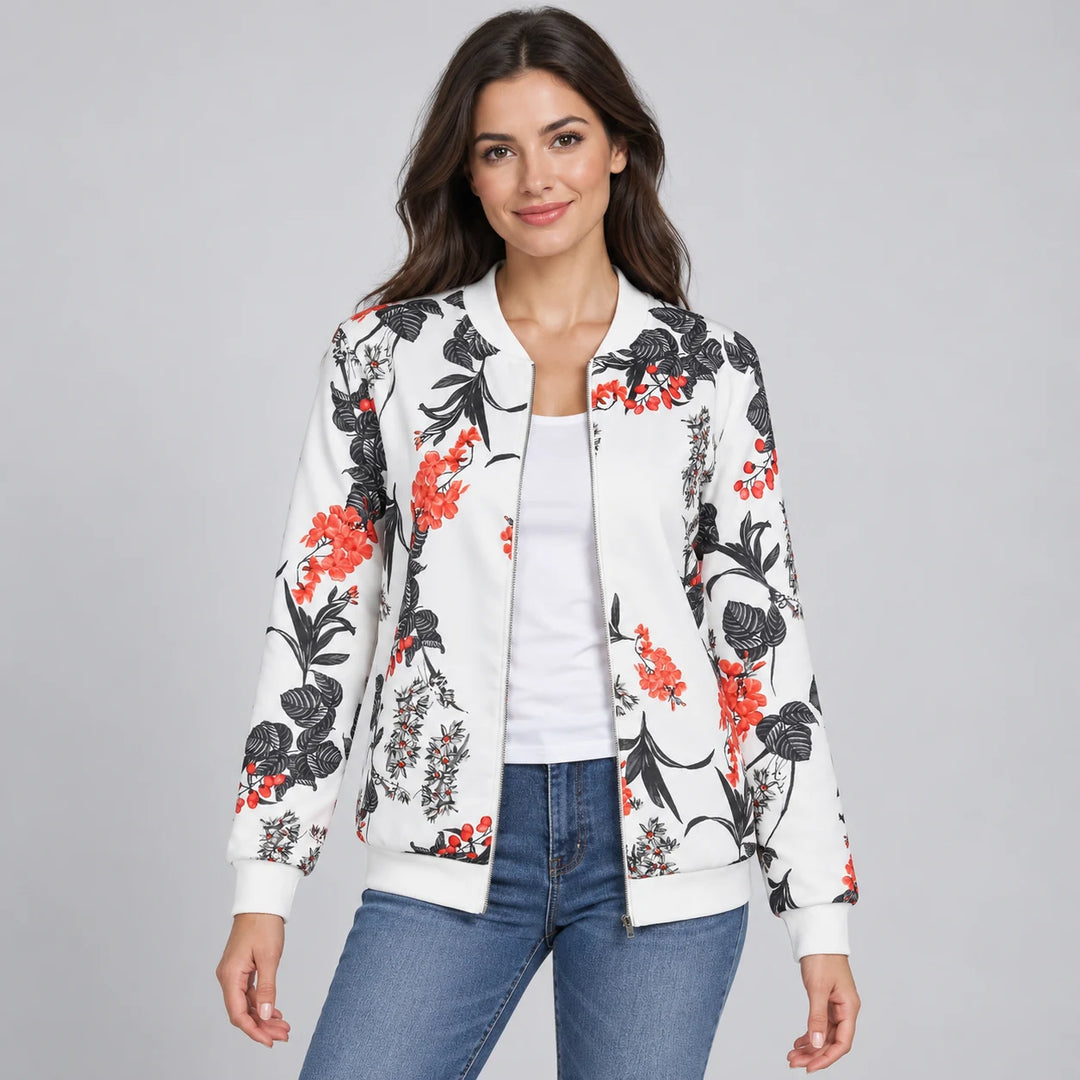 Model wearing the White botanical zip-up jacket with blue jeans, showing coral-red blossoms and large black leaves and cuffs.