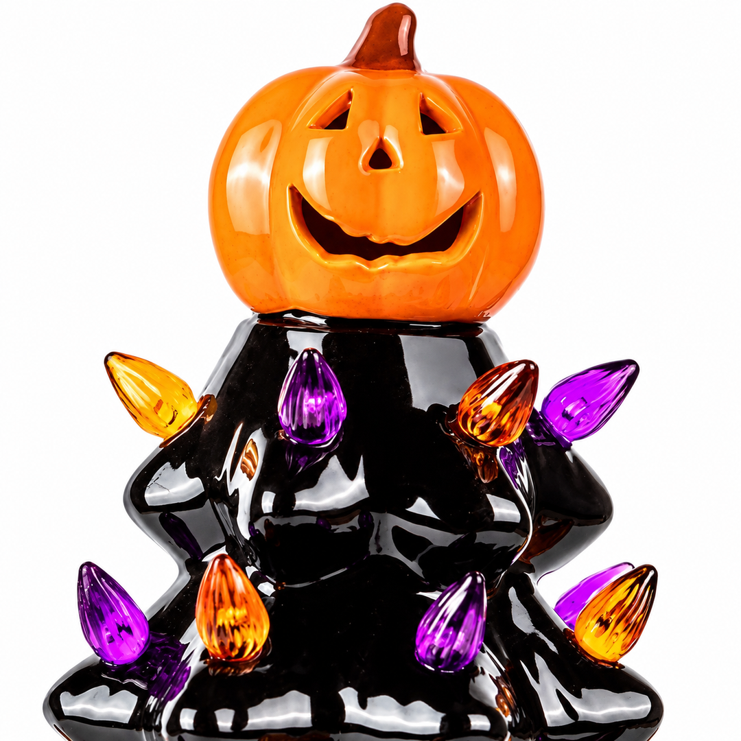 Detail of the orange jack-o-lantern topper and upper black tree tiers with purple and amber details against a white backdrop.