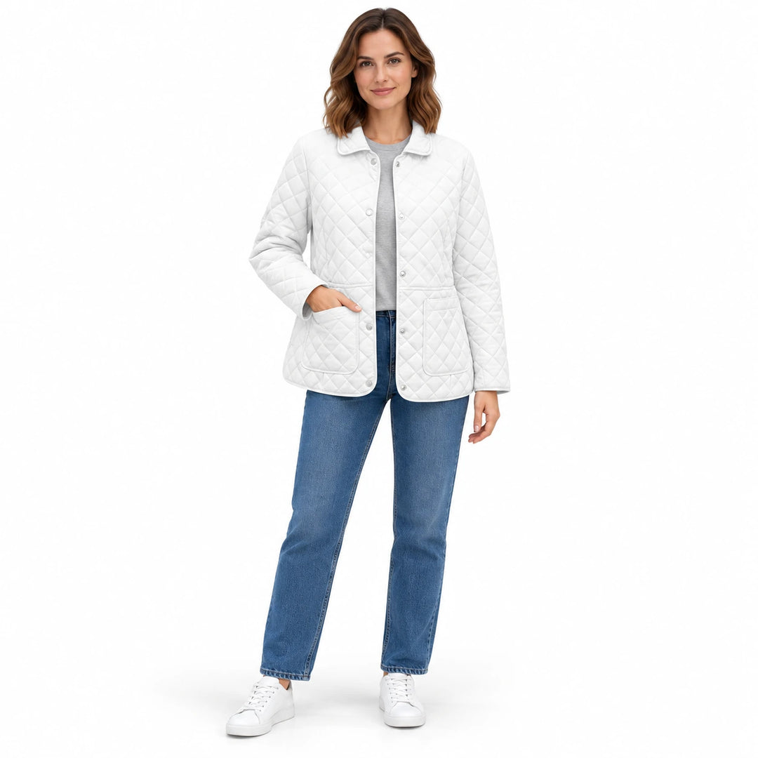 White quilted jacket worn by a female wearer, with a collar, silver snaps and rounded pockets, shown at full length on white.