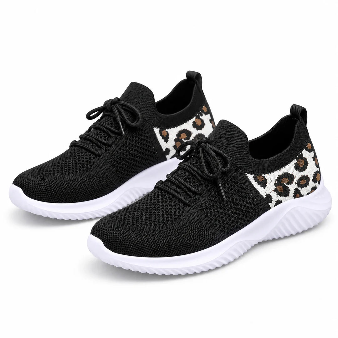 Leopard print sneakers in black mesh with white soles and tan spotted heel panels, shown paired on a white studio background.