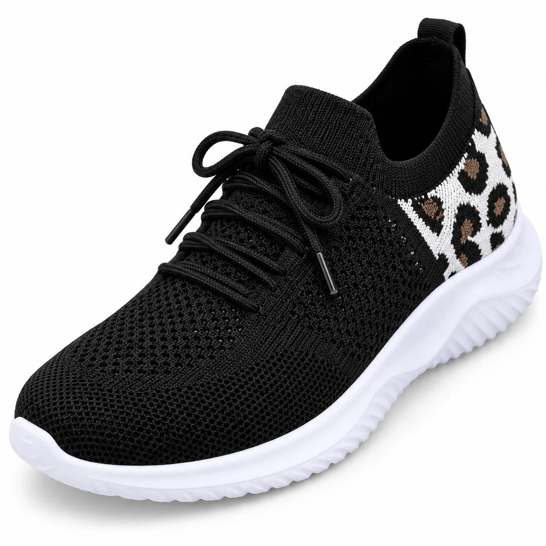 Close view of black laces and knitted mesh over the front of a sneaker, showing the tongue and round toe on white background.