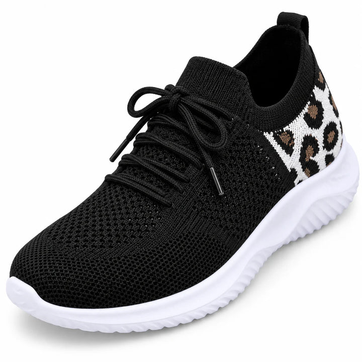 Close view of black laces and knitted mesh over the front of a sneaker, showing the tongue and round toe on white background.