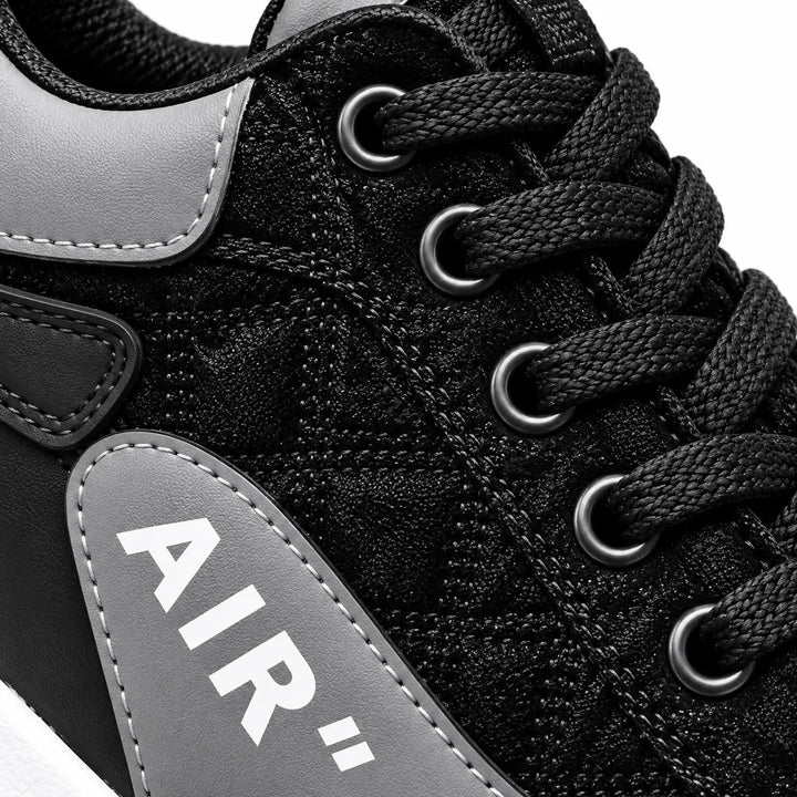 Close-up of Black and Gray sneaker laces and eyelets with gray collar edge, patterned black upper and partial AIR side panel.