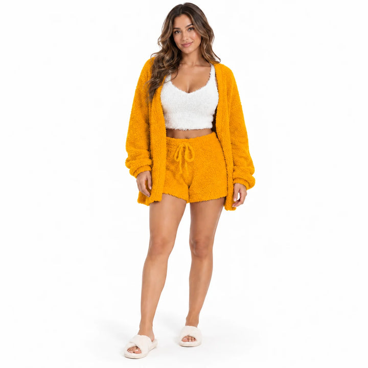 Studio model wearing a golden yellow lounge coat and shorts with a white cropped vest, front view on white studio background.