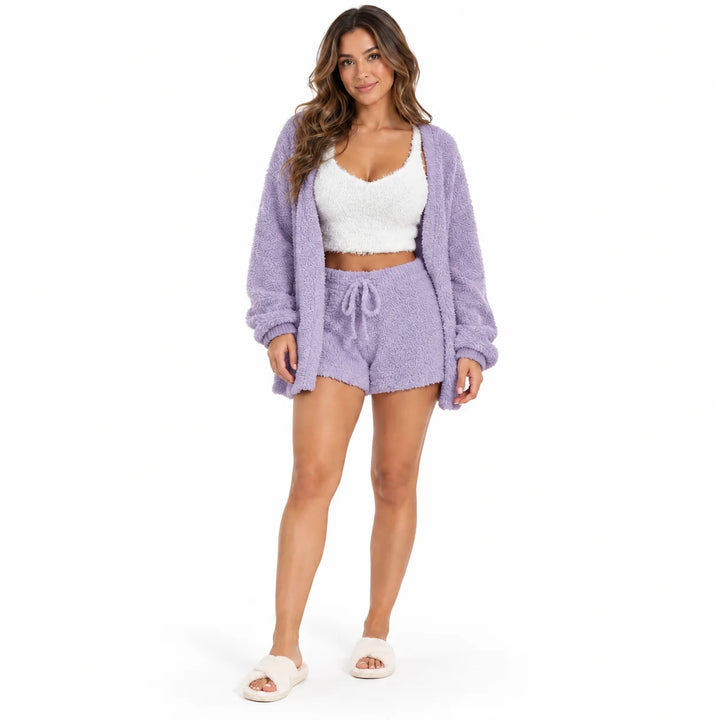 Full-body model wearing a lavender coat and drawstring shorts, with a white cropped vest on a bright white studio background.