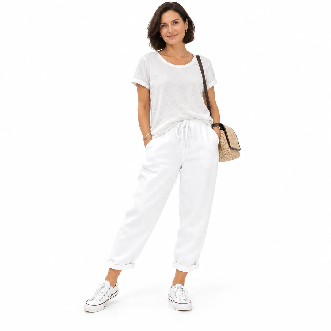 White drawstring ankle pants on a standing adult woman, showing the ankle length and drawstring, on a plain white background.