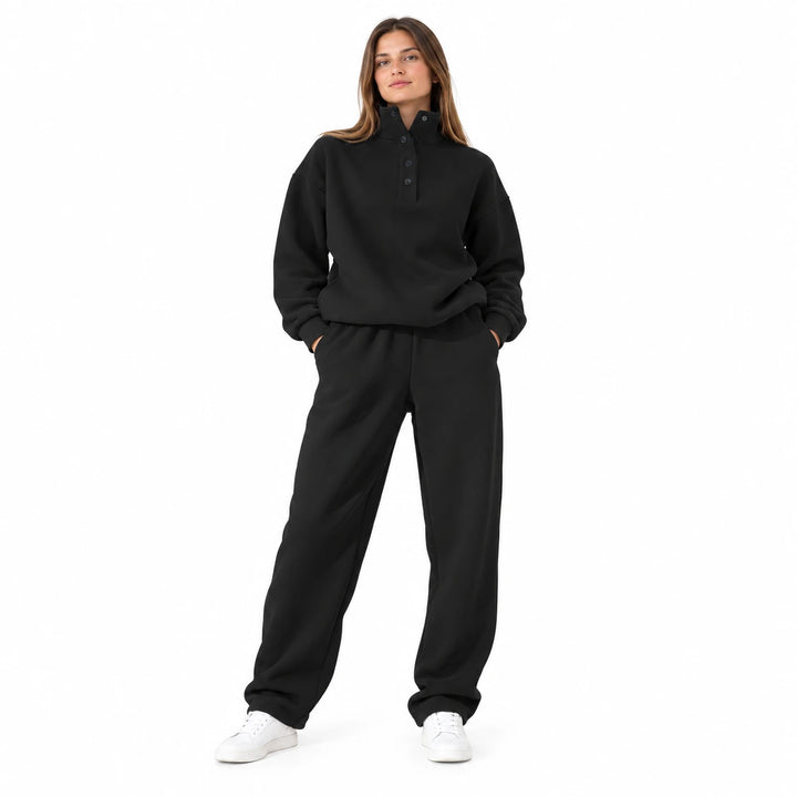 Black matching set with a stand collar and dark buttons, worn by an adult model in a front view on a white studio background.