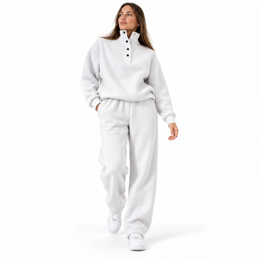 White matching set with a stand collar and dark buttons, worn by an adult model in a studio walking pose on a white backdrop.