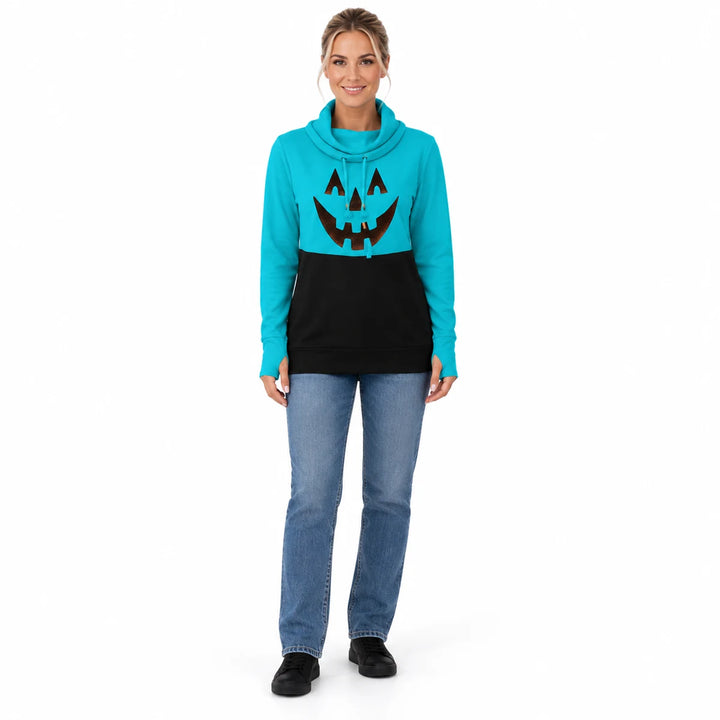 Woman wearing a turquoise blue and black pumpkin print pullover with jeans and black shoes in a full-body front studio photo.