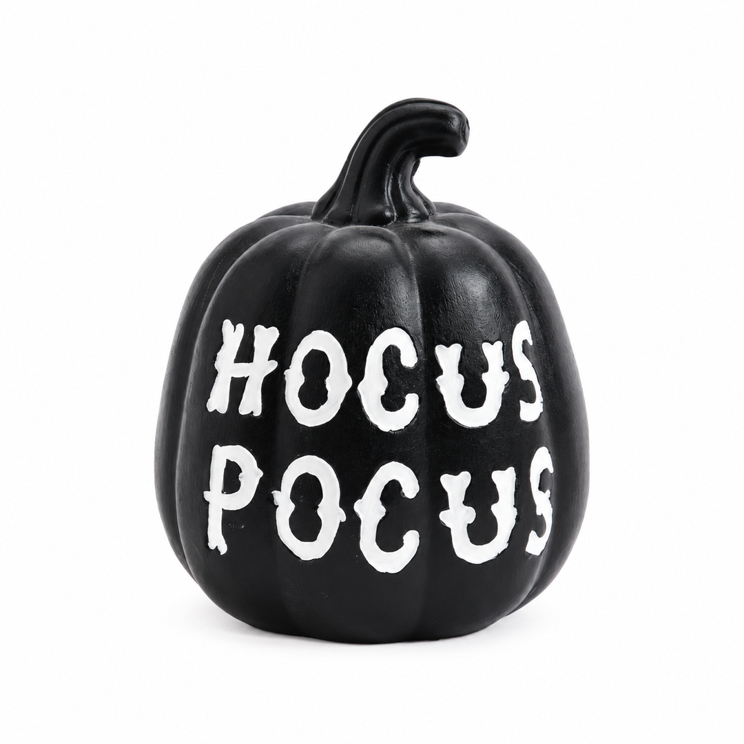 Frontal view of the black Halloween pumpkin with HOCUS POCUS lettering, molded grooves and a curved stem on a white backdrop.