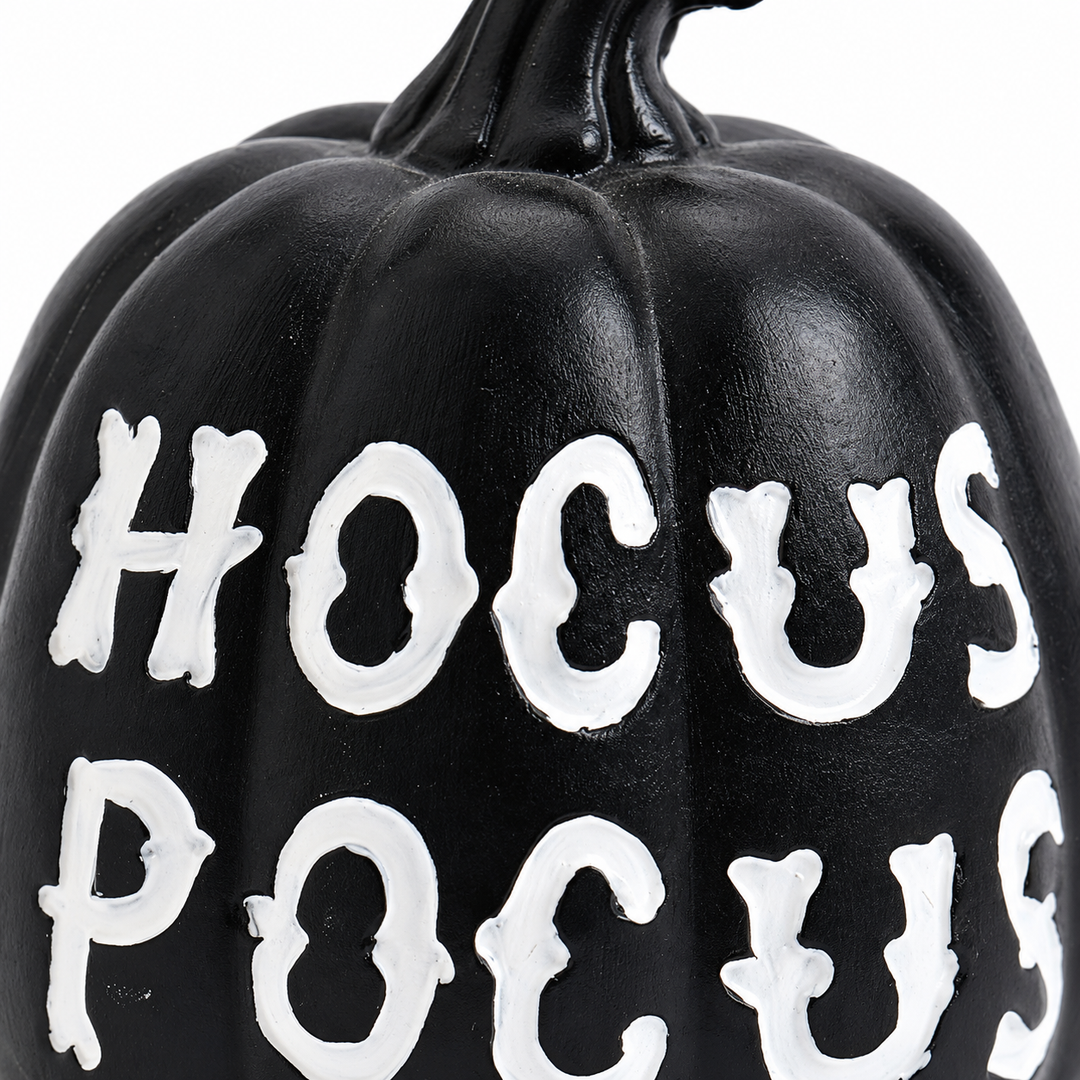 Close-up of the black pumpkin surface, molded grooves and white HOCUS POCUS lettering, photographed against a white backdrop.