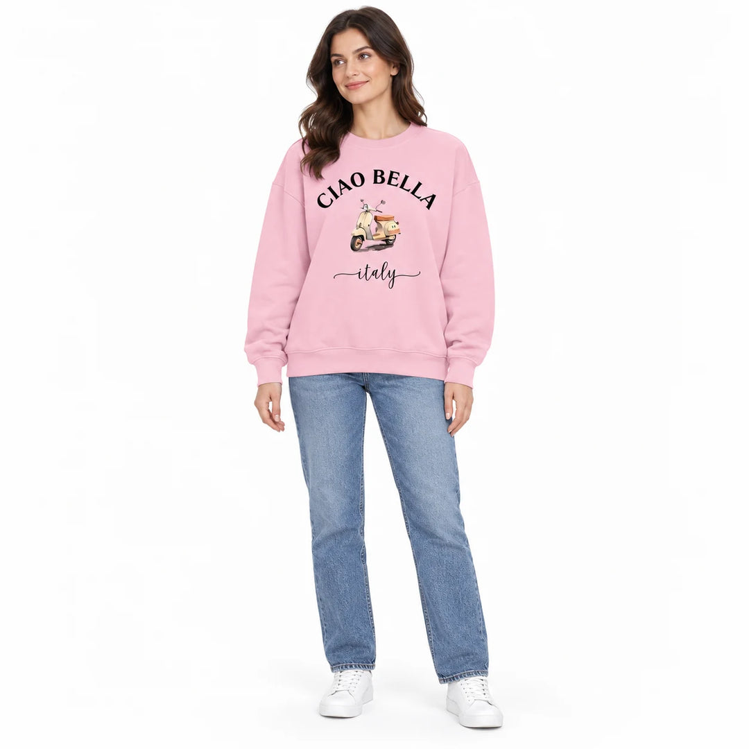Pink crew neck sweatshirt with black Ciao Bella lettering and a scooter print, shown on a female model on a white background.
