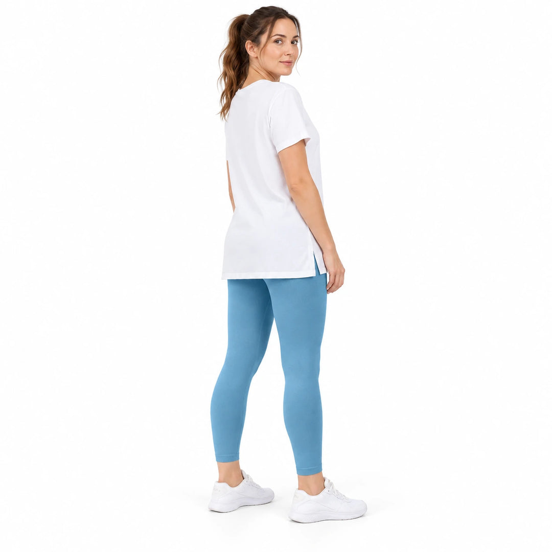 Adult model in Sweet Blue contoured leggings, a long white T-shirt and white trainers, standing on a white studio background.