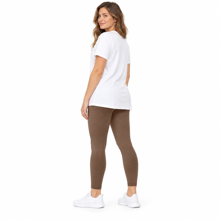 Adult model in Coffee contoured leggings, a white longline T-shirt and white trainers, standing on a white studio background.