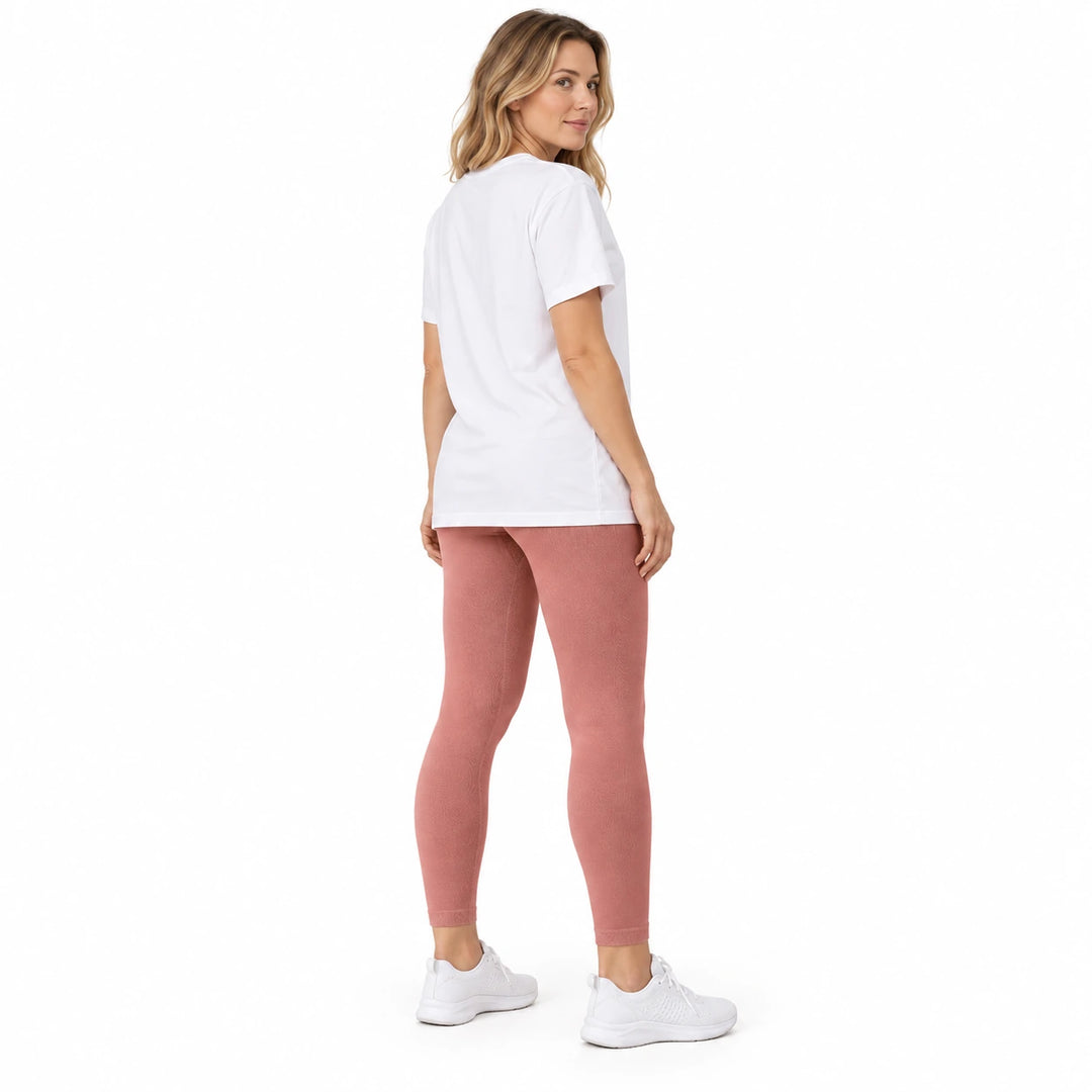 Adult model in Quicksand Powder leggings, a white longline T-shirt and white trainers, standing on a white studio background.