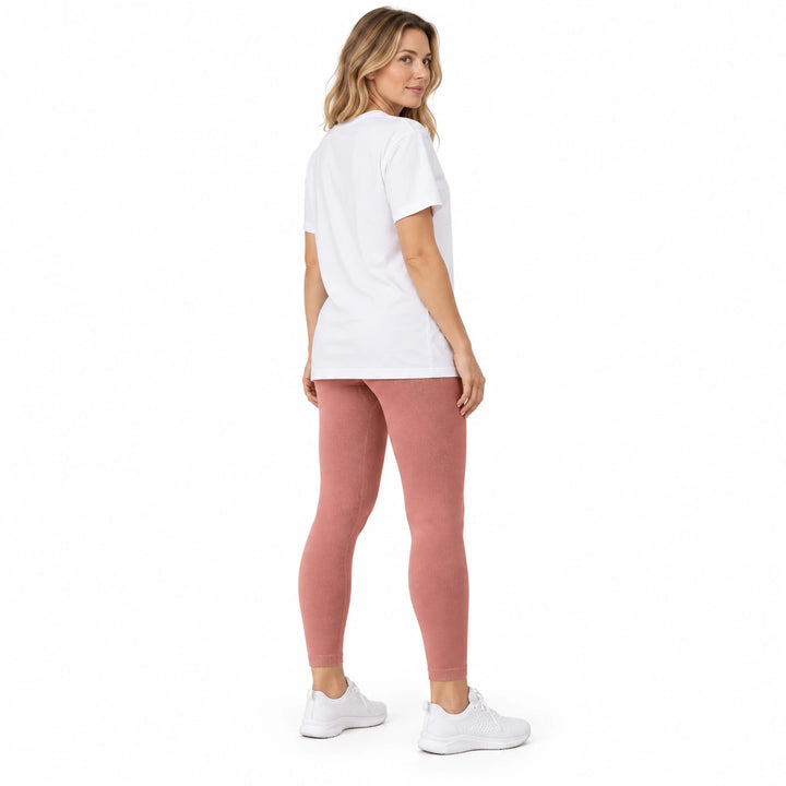 Adult model in Quicksand Powder leggings, a white longline T-shirt and white trainers, standing on a white studio background.