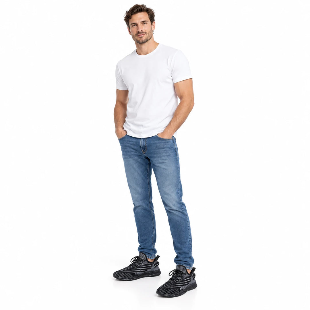 Adult male model wearing black mesh sneakers with blue jeans and a plain white T-shirt, fully visible on a plain white scene.
