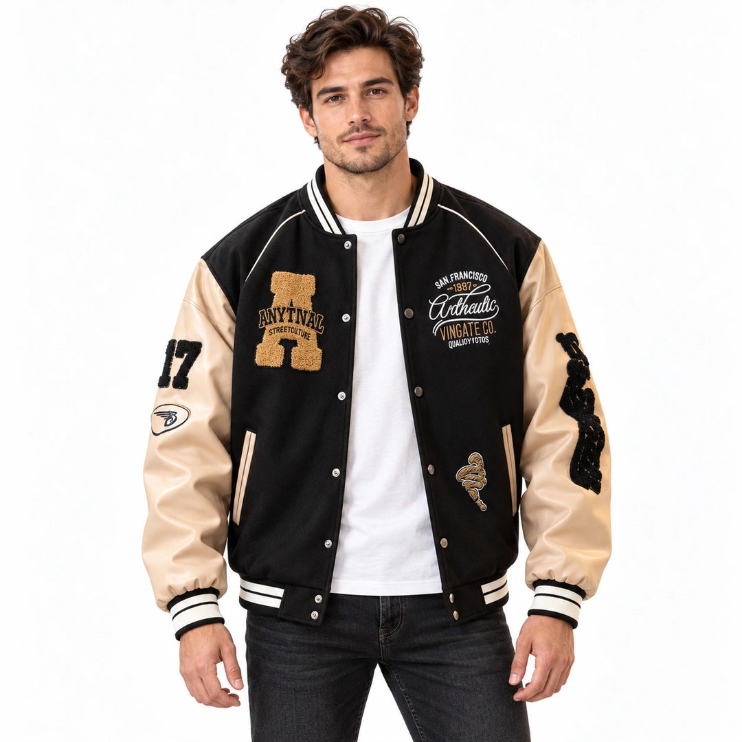 Male model wearing the Black varsity jacket with cream sleeves over a white T-shirt and jeans on a white background.