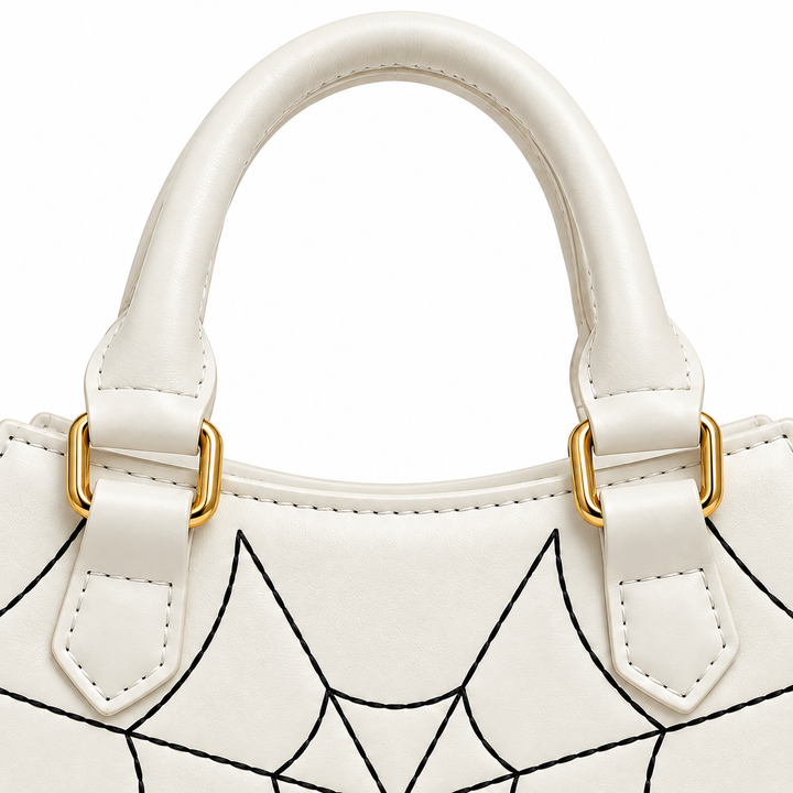 Close view of the white rounded carry handle, attachment tabs, gold-tone rectangular rings and stitching above the black web.