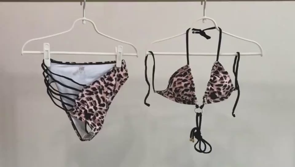 videoModel showcasing the leopard print cutout strap swimsuit on a sunlit beach with gentle waves in the background