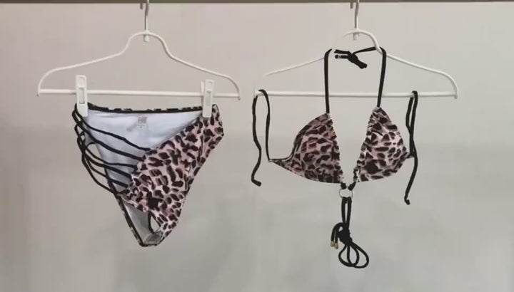 videoModel showcasing the leopard print cutout strap swimsuit on a sunlit beach with gentle waves in the background