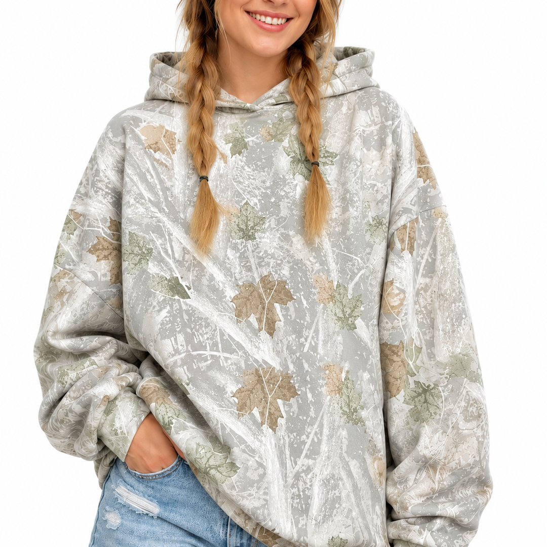 Woman wearing the printed pullover hoodie with the hood up, displaying the mixed-color print and long sleeves on white.