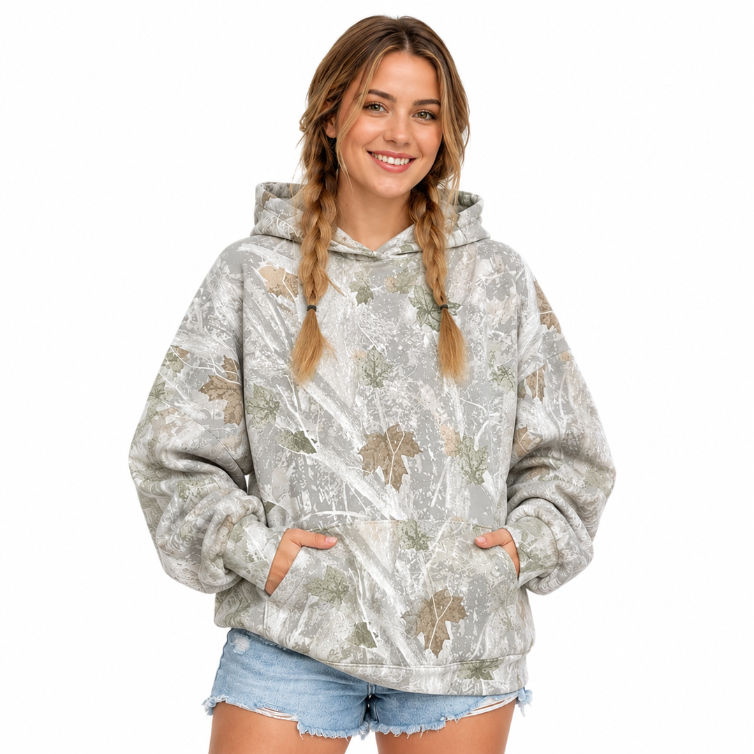 Woman wearing the printed pullover hoodie with both hands at the front pocket, shown on a clean white studio background.