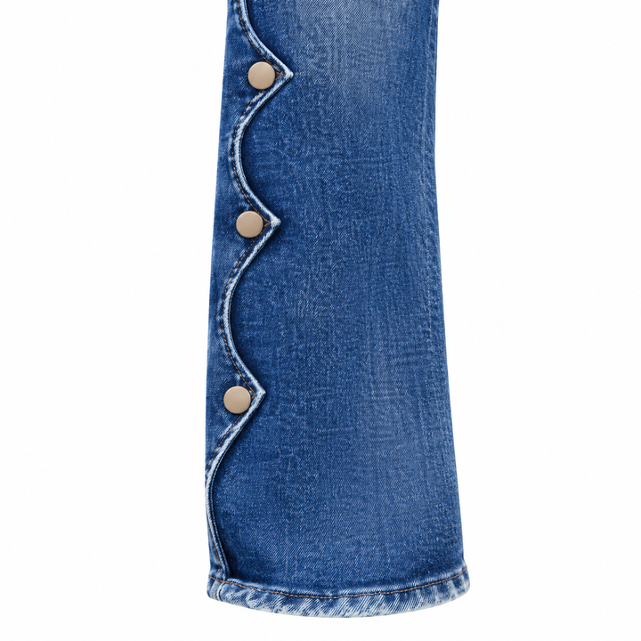Close-up of scalloped blue denim lower-leg trim and side buttons.