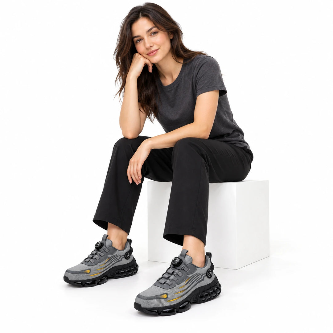 Female model wearing grey athletic steel toe shoes with yellow accents and black trousers.