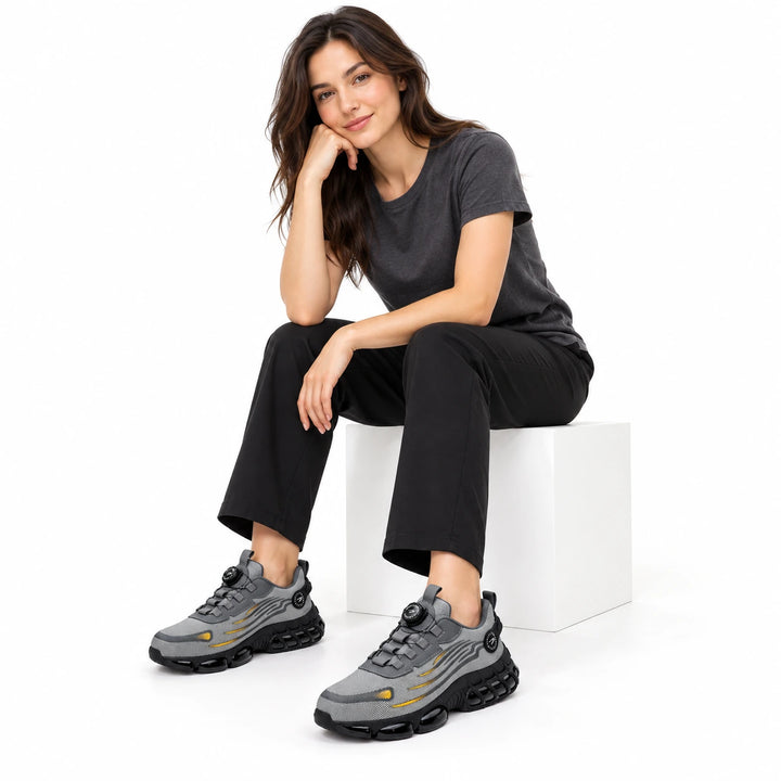 Female model wearing grey athletic steel toe shoes with yellow accents and black trousers.