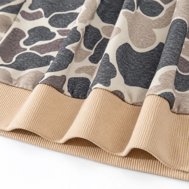Close-up of the beige ribbed waistband and gathered camouflage fabric, showing the hem stitching and cream and charcoal print
