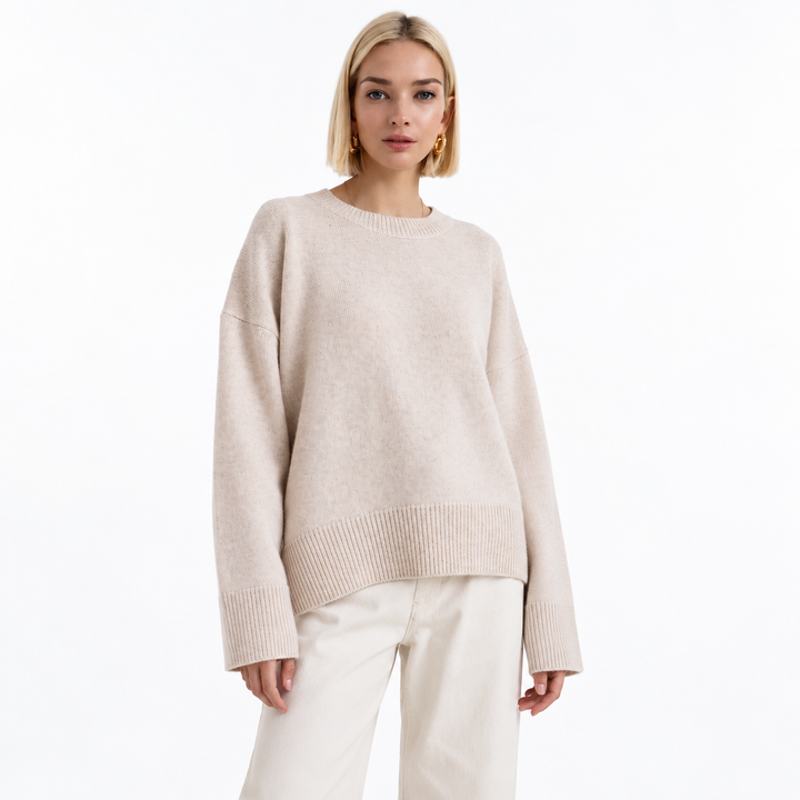 Apricot knit pullover shown on a model against white, with a crew neckline, dropped shoulders, long sleeves and ribbed edges.