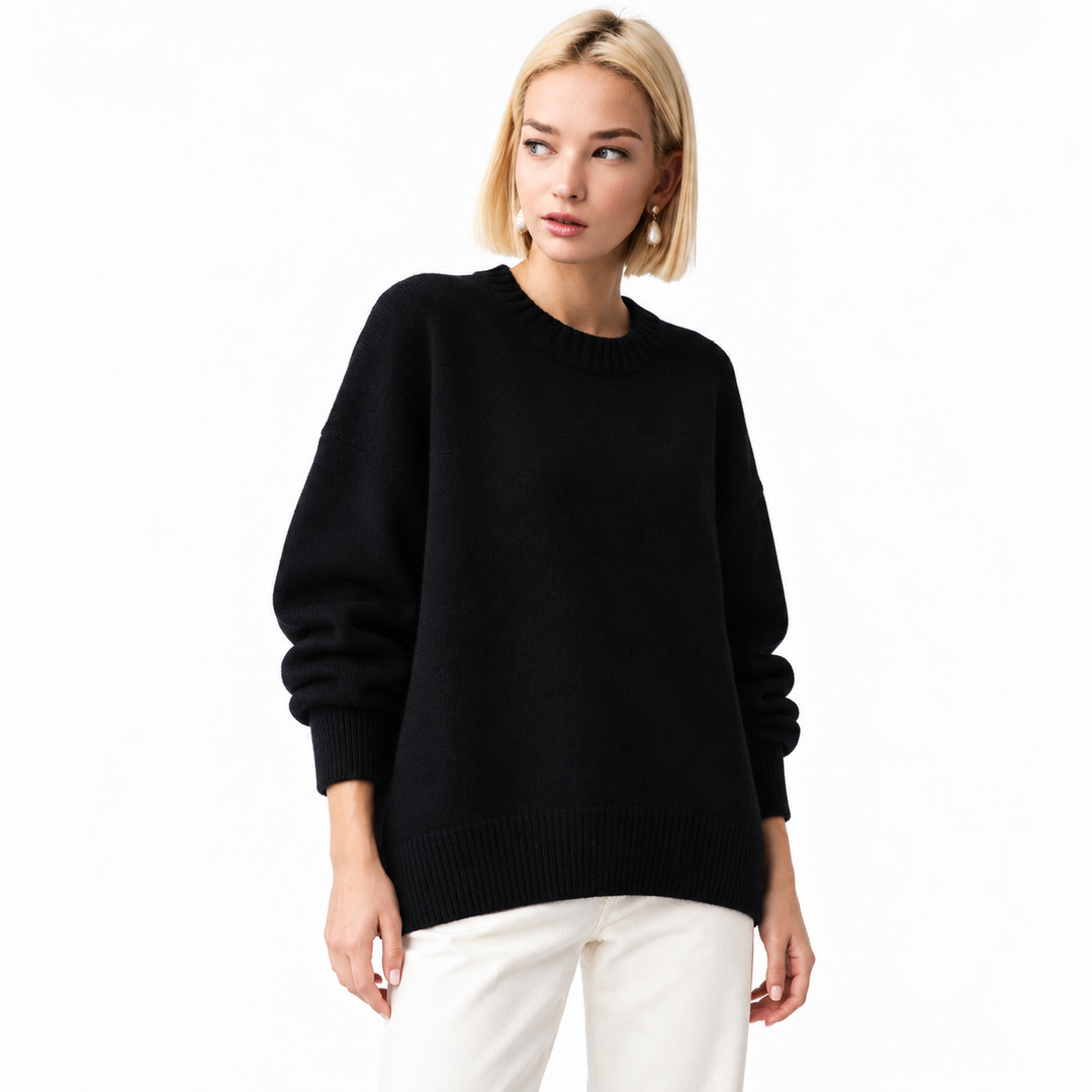 Black knitted pullover on a model in a white studio, showing its crew neckline, long sleeves, relaxed shape and ribbed edges.