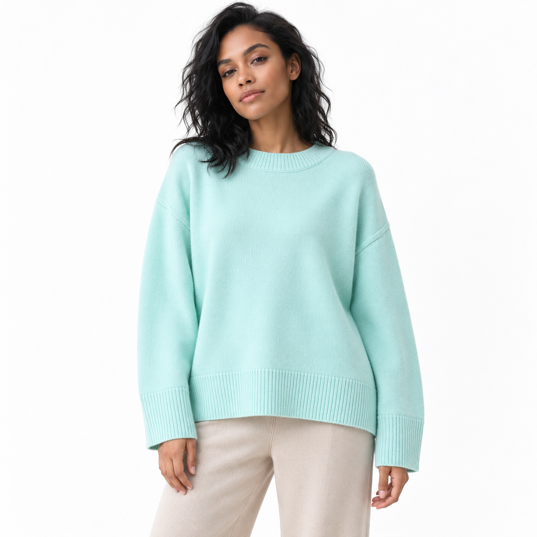 Emerald knit pullover shown on a model against white, with a crew neckline, dropped shoulders, long sleeves and ribbed edges.