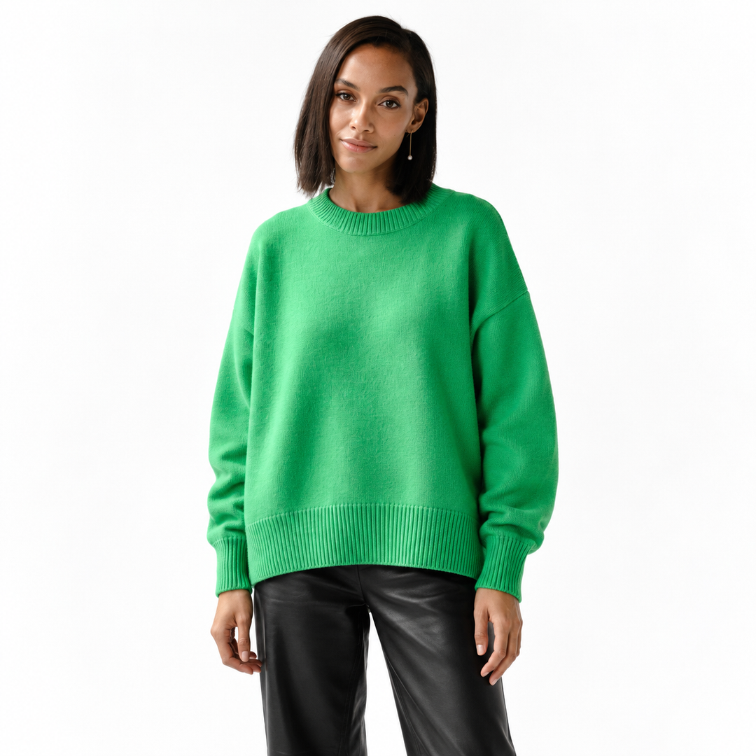 Greenish knitted pullover on a model in a white studio, showing long sleeves, ribbed cuffs, a round neckline and relaxed fit.