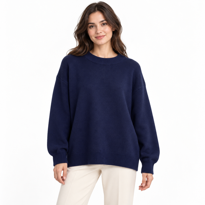 Navy blue knit pullover on a model against white, showing its round neckline, long sleeves, relaxed fit and ribbed finishing.