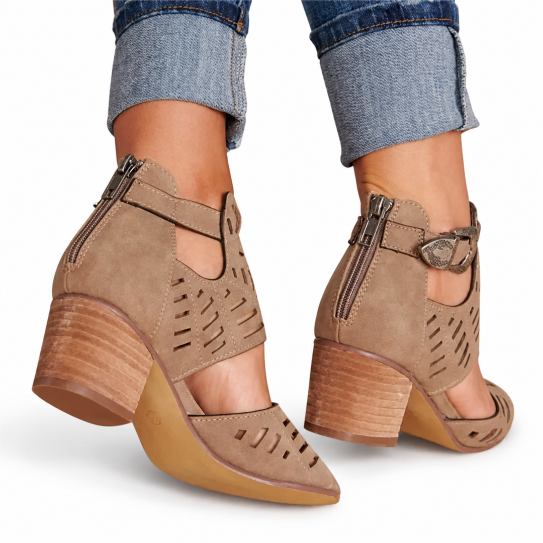 Rear view of brown cutout sandals with back zips, side buckles and broad heels, worn with cuffed jeans on a white background.