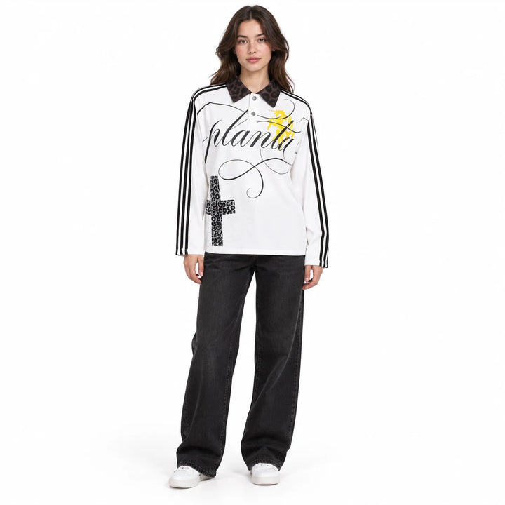 Adult female model wearing the White collared polo shirt with black sleeve stripes, cross print and a black patterned collar.