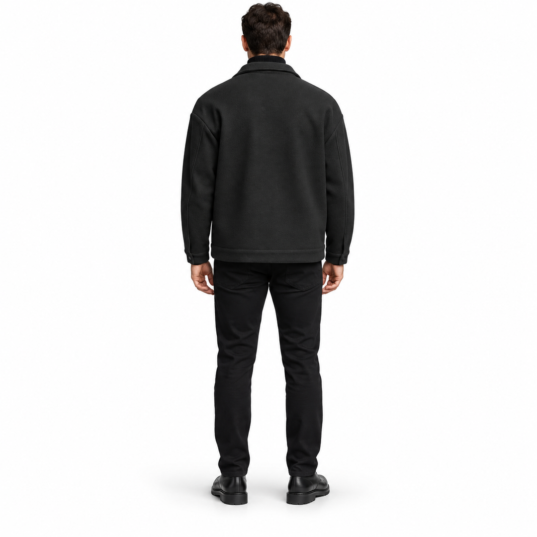 Rear view of the black jacket on a full-length male model, showing shoulder yoke, plain back panel and stitched hem on white.