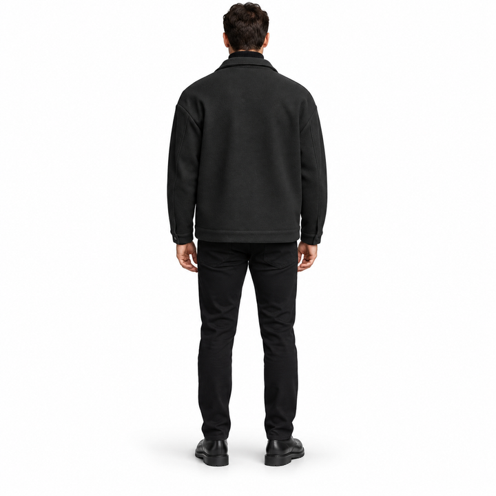 Rear view of the black jacket on a full-length male model, showing shoulder yoke, plain back panel and stitched hem on white.