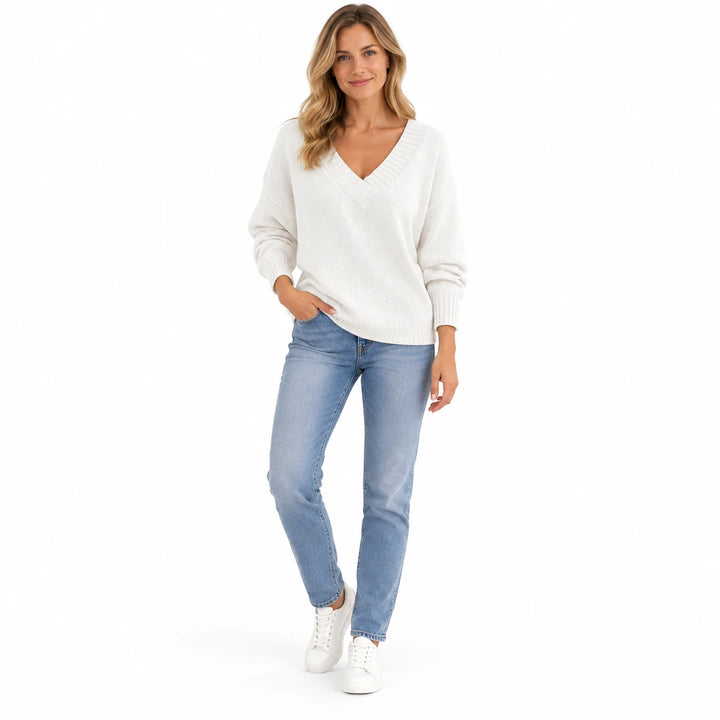 Adult woman shown wearing the White V-neck knit pullover, in a full-body studio view against a plain white studio background.